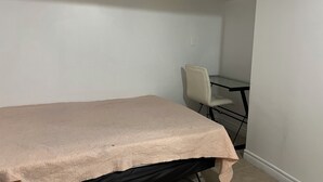 Una habitación pequeña y poco amoblada con una cama individual, una silla y un escritorio.
