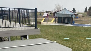Boblebad med trin, en indhegnet terrasse og en legeplads i baggrunden.