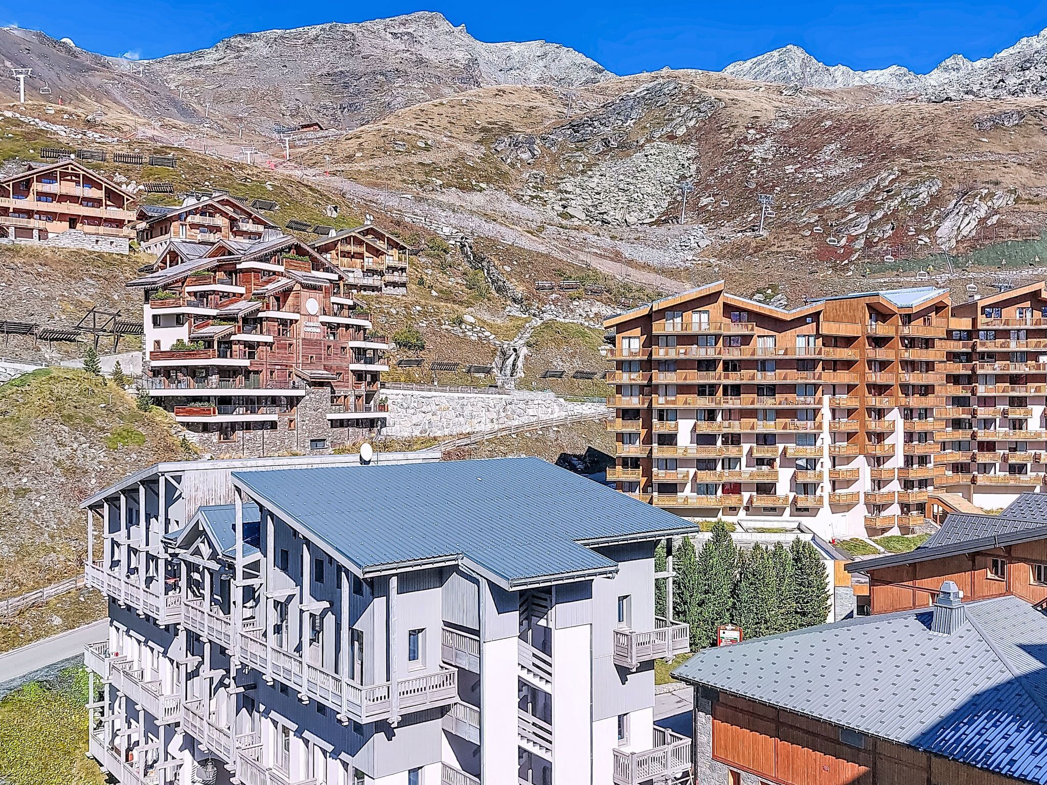 A mountain resort with multi-story wooden buildings, ski lifts, and rocky terrain.
