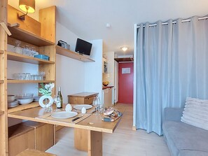 A compact living space with a kitchenette, dining area, and a sofa.