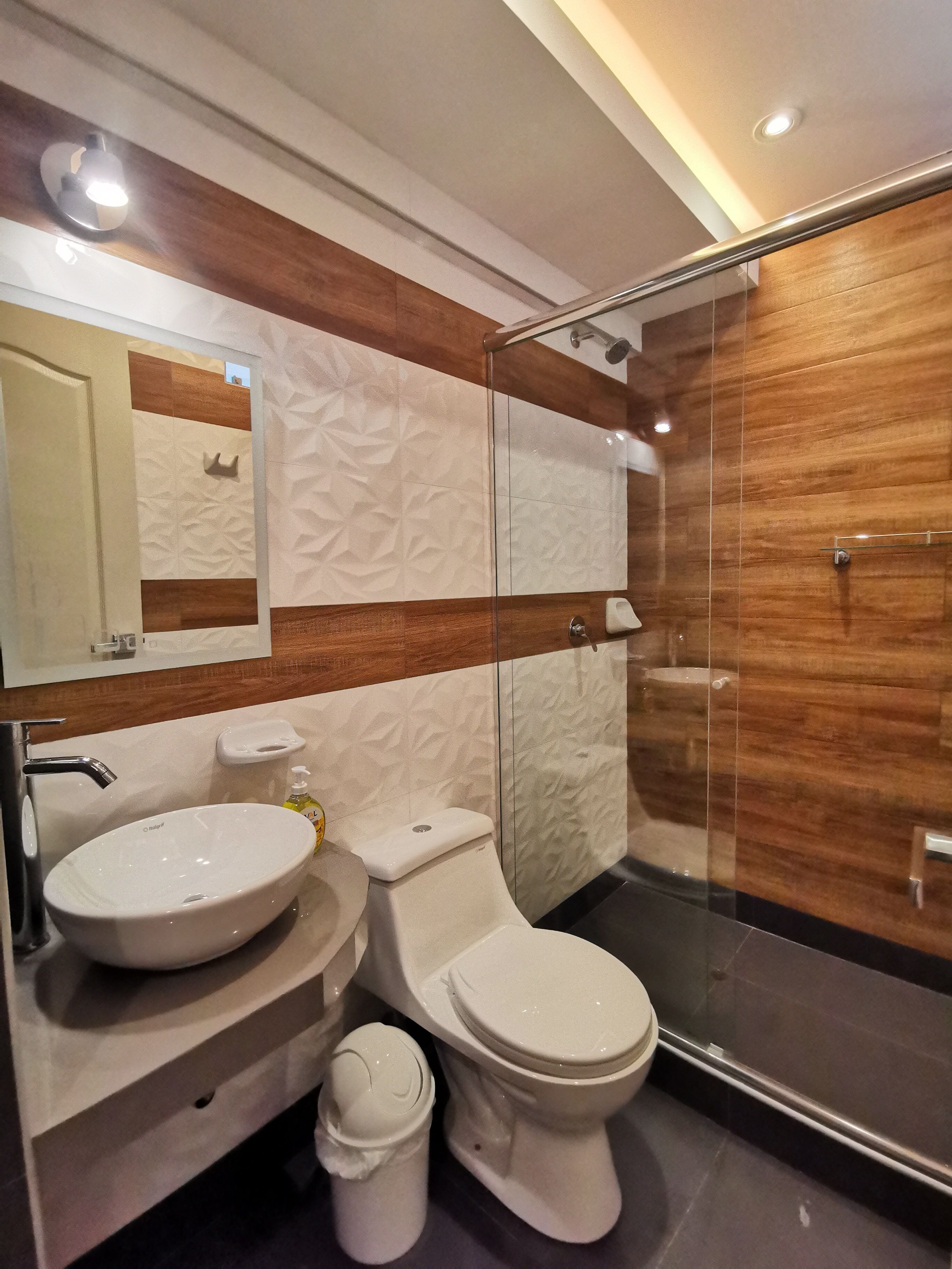 A modern bathroom with a glass-enclosed shower, a white sink, and a toilet.