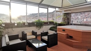 A rooftop patio with outdoor furniture, a hot tub, and a city view. - Suites Cusco (Cusco)