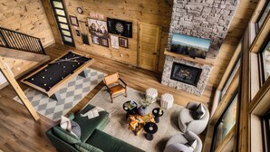 A cozy room with a pool table, green sofa, and a fireplace. - Chara Vista Cabin: A Smoky Mountain Retreat (Sevierville)