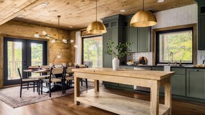 A rustic kitchen with wooden beams, a large island, and pendant lighting. - Chara Vista Cabin: A Smoky Mountain Retreat (Sevierville)