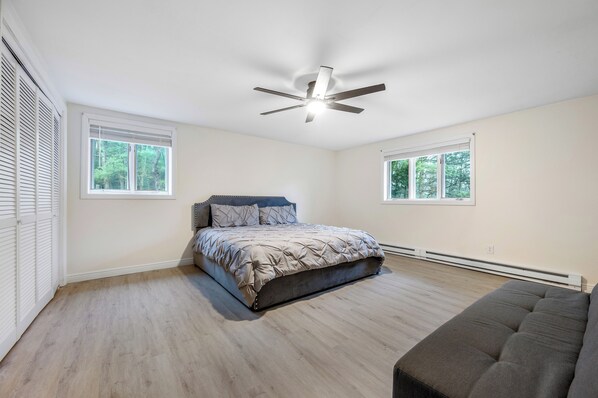 A bedroom with a bed, a ceiling fan, and two windows. - Features two living rooms, sauna, hot tub, and fire pit -over 4 acres of land. (Stroudsburg)