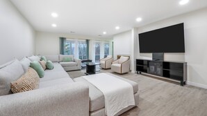 A modern living room with a sectional sofa, armchairs, a flat-screen TV, and a fireplace. - Features two living rooms, sauna, hot tub, and fire pit -over 4 acres of land. (Stroudsburg)