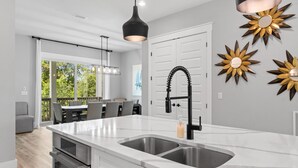 Una cucina moderna con un'ampia isola, elettrodomestici in acciaio inossidabile e un rubinetto nero.