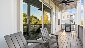 Un portico riparato con due poltrone Adirondack, una ventola a soffitto e un barbecue.