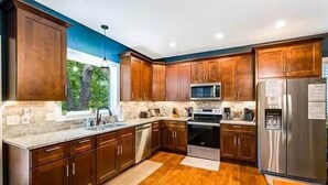 Une cuisine moderne avec des meubles en bois, des appareils électroménagers en acier inoxydable et une grande fenêtre.