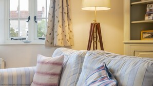 A room with a striped sofa, a lamp, and a window with curtains.