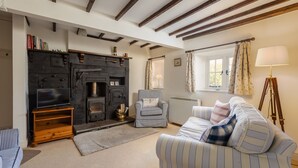 A cozy living room with a fireplace, striped sofa, and a television on a wooden stand.