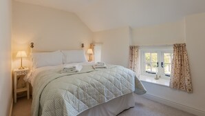 A bedroom with a bed, nightstands, lamps, and a window with curtains.