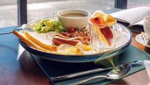 A breakfast plate with eggs, bacon, toast, and fruit, served on a tray with a cup of coffee and a glass of juice, in front of a window with a snowy mountain view. - Blue Spot Resort (Ulaanbaatar)