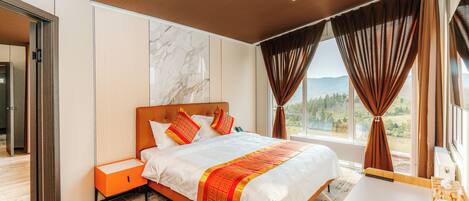 A modern hotel room with a large bed, a bedside table, a small desk, and a view of the outdoors.
