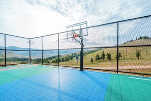 An outdoor basketball court with a chain-link fence, a basketball hoop, and a green and blue playing surface. - Blue Spot Resort (Ulaanbaatar)