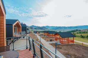 A view of a resort with wooden cabins, a deck, and a mountain backdrop. - Blue Spot Resort (Ulaanbaatar)