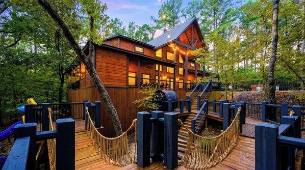 A wooden cabin with a deck, surrounded by trees.