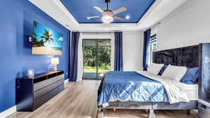 A bedroom with a bed, a ceiling fan, a nightstand, a dresser, and a window with curtains. - Brand New, Family Friendly Spacious- Home Sleeps 12 + 10 mins to Gulf Beaches (Englewood)