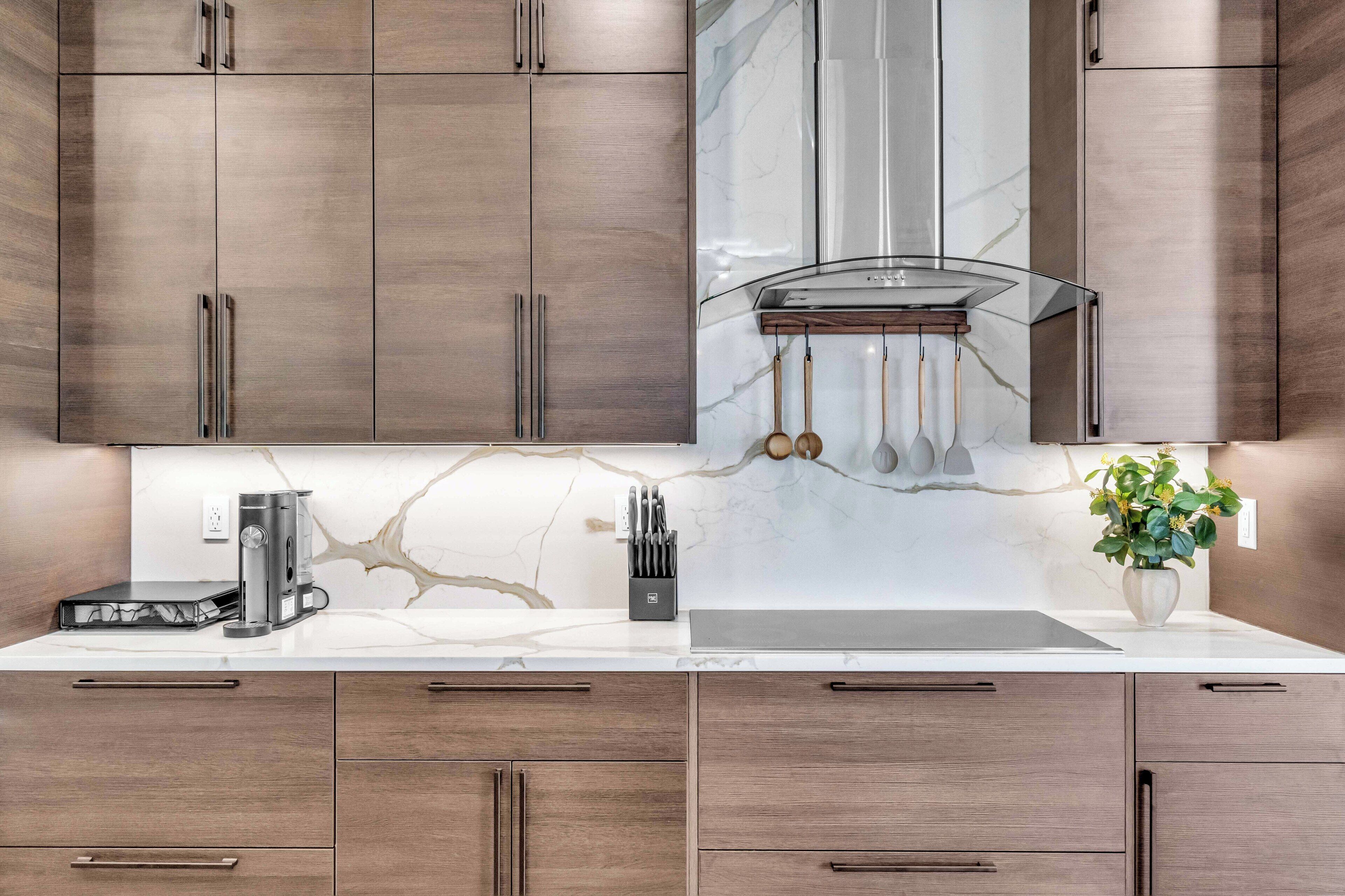 Une cuisine moderne avec des meubles en bois, un pare-feu en marbre et des appareils électroménagers en acier inoxydable.