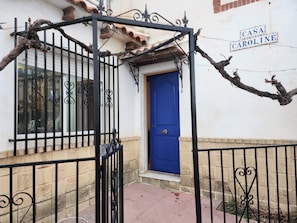 A blue door with a wrought iron gate in front, a brick wall, and a sign that reads 'CASA CAROLINE'.