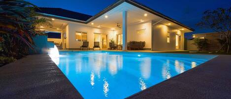 Una piscina al aire libre, sillones reclinables de piscina