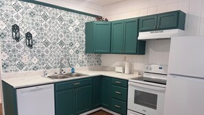 Eine Küche mit grünen Schränken, einem Geschirrspüler von Bosch, einem Whirlpool-Ofen und einem weißen Kühlschrank.