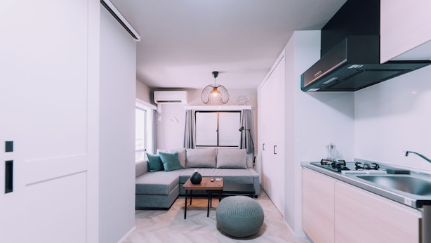 A modern kitchen with a built-in stove, a sink, and a compact dining area with a sofa and a small table. - Showa Bloom · Cozy Stay Near Shinjuku (Tokyo)