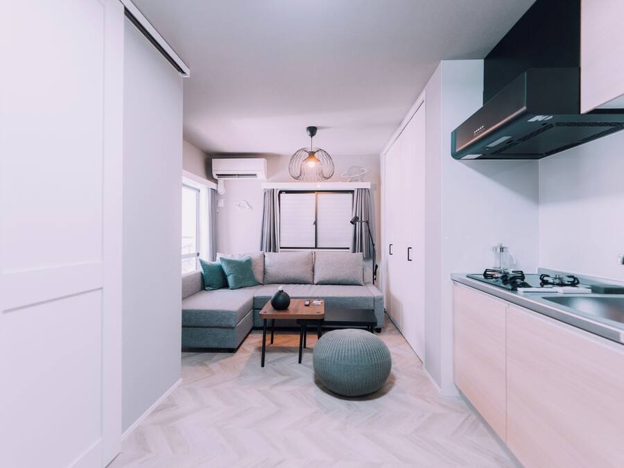 A modern kitchen with a built-in stove, a sink, and a compact dining area with a sofa and a small table.