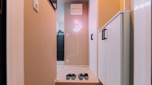 A hallway with a neon cat sign, a refrigerator, and a pair of slippers on a step. - Showa Bloom · Cozy Stay Near Shinjuku (Tokyo)