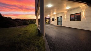A building with a covered entrance, a paved driveway, and a grassy area. - Harbour View Lodge (Porirua)