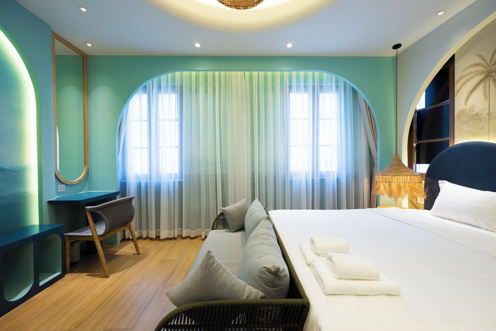 A modern hotel room with a large bed, a desk, and a chair.