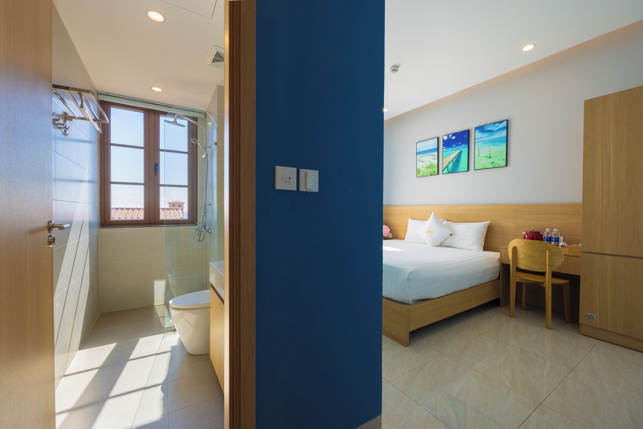 Een hotelkamer met douche, toilet, bed en bureau met stoel.