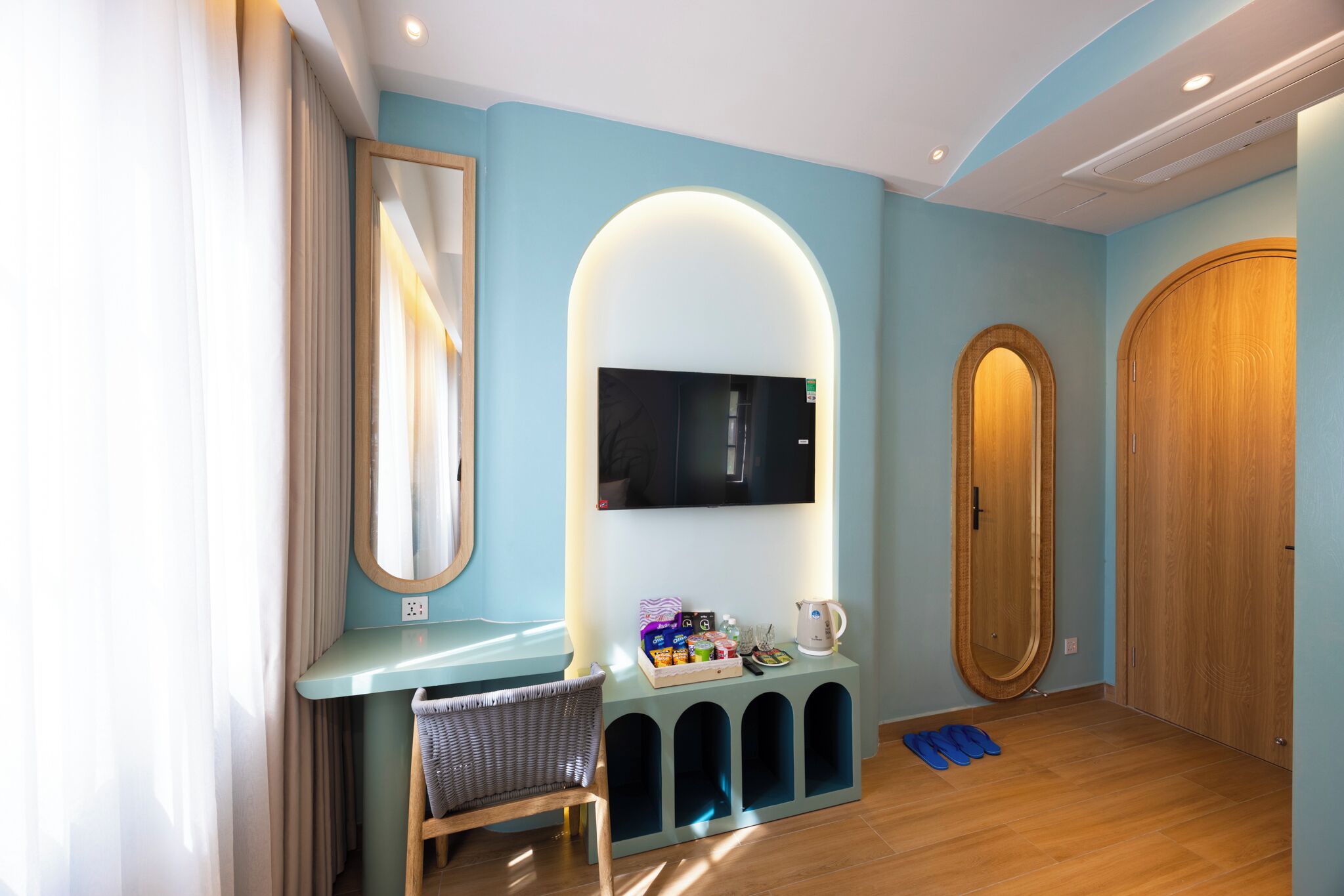Un bagno moderno con un mobile lavabo, uno specchio, una televisione e una porta in legno.