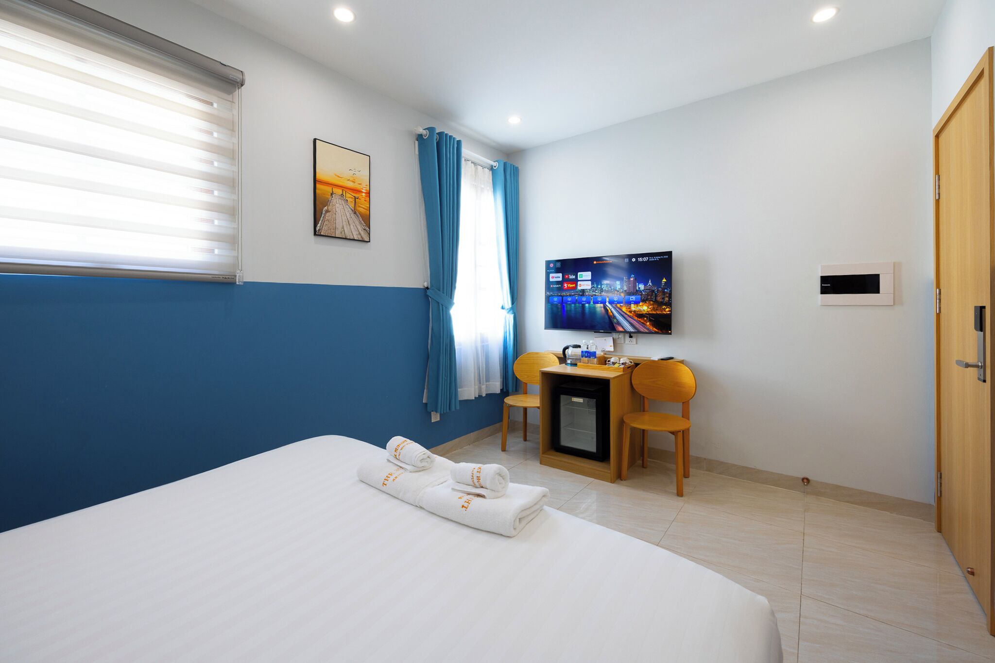 A hotel room with a bed, a desk, a television, and a door.