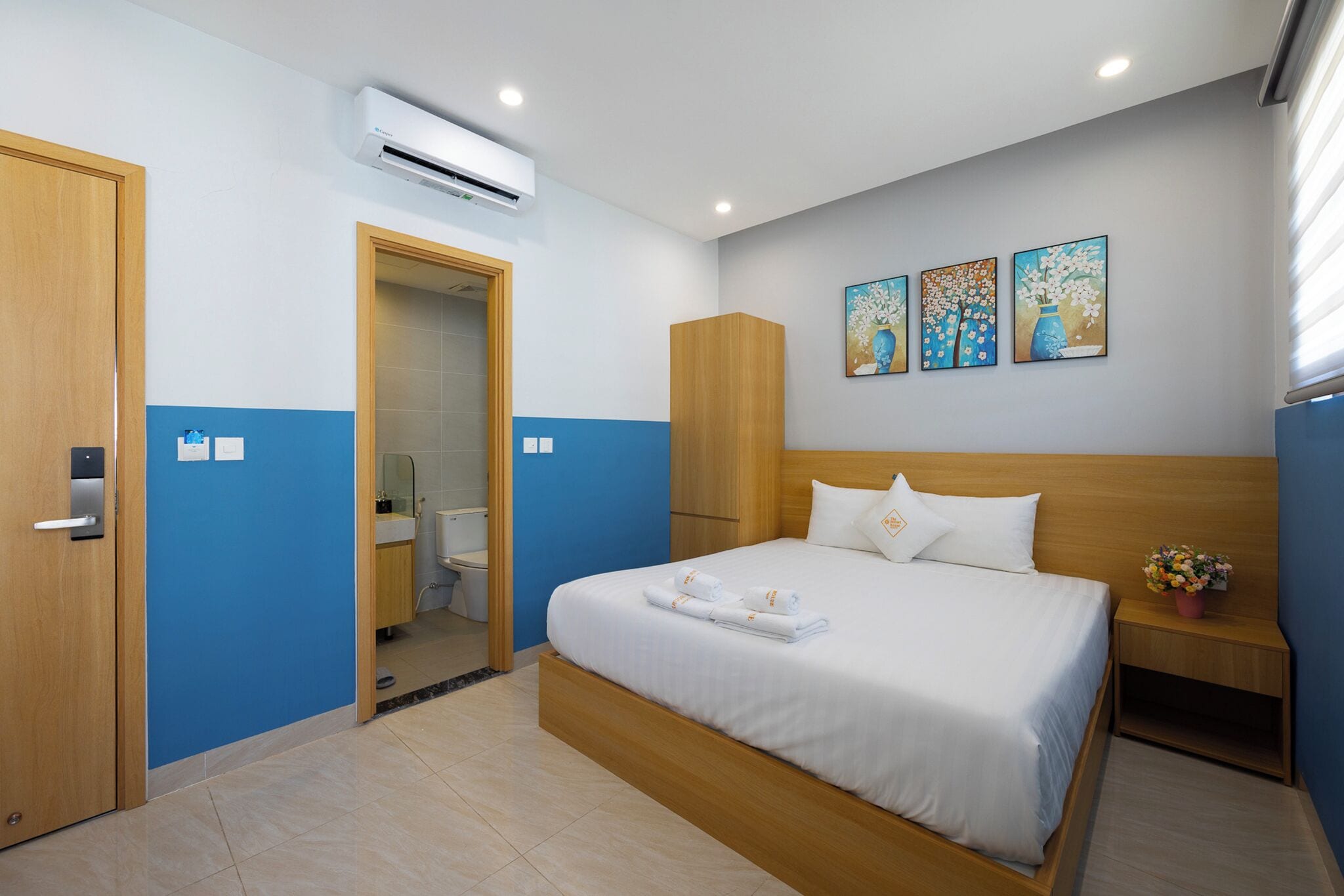 Ein Hotelzimmer mit einem Bett, einem Holzschrank, einem Badezimmer und drei Bildern an der Wand.
