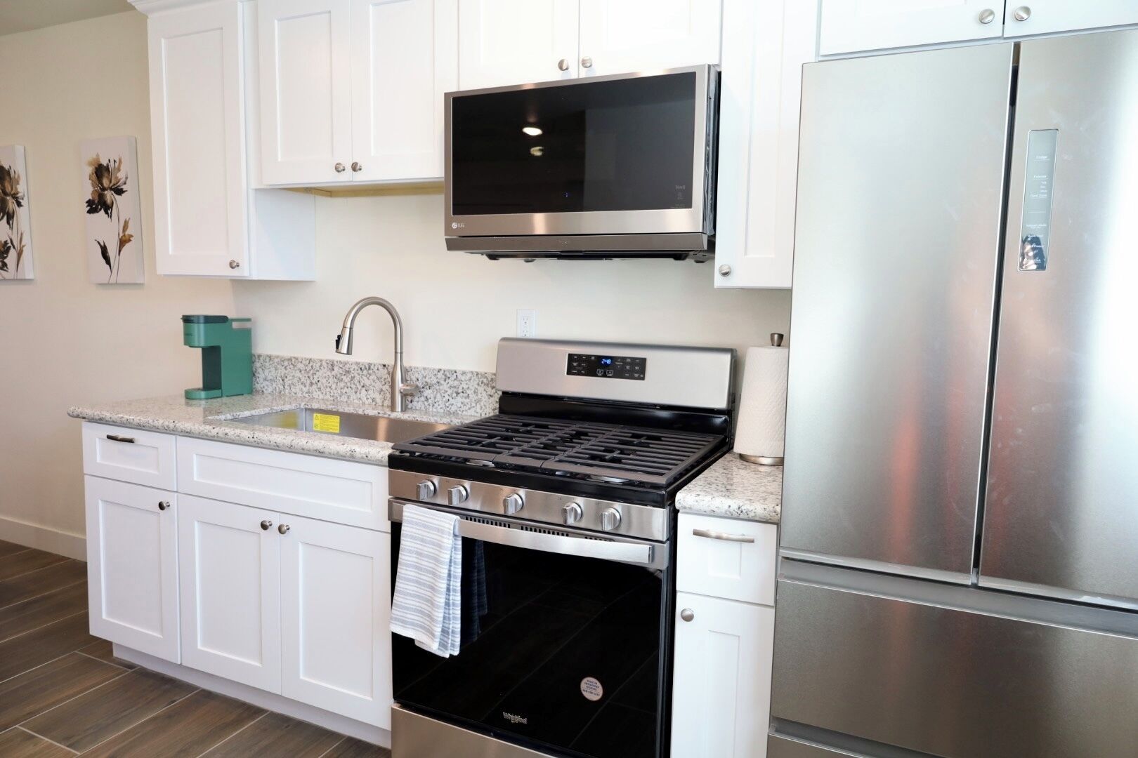 A modern kitchen with white cabinets, a stainless steel refrigerator, a built-in microwave, a gas stove, and a dishwasher.