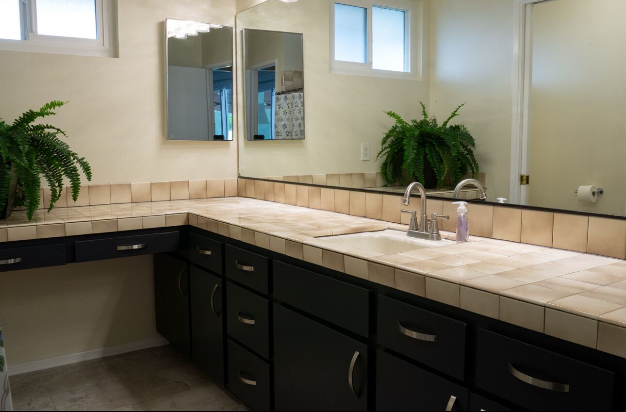 A modern bathroom with a double sink, dark cabinetry, and two large mirrors.
