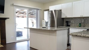 Eine moderne Küche mit weißen Schränken, einem Edelstahlkühlschrank und einer Arbeitsplatte aus Granit.