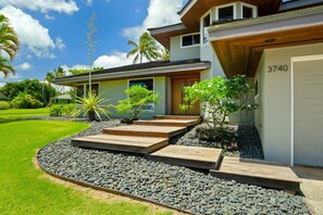 Une maison moderne avec une pelouse bien entretenue, une allée menant à la maison avec des marches en bois et un garage portant le numéro 3740.