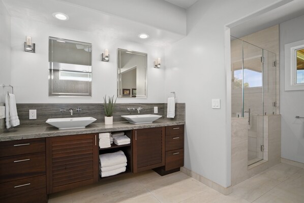 Une salle de bain moderne avec deux lavabos, un grand miroir et une douche à parois de verre.