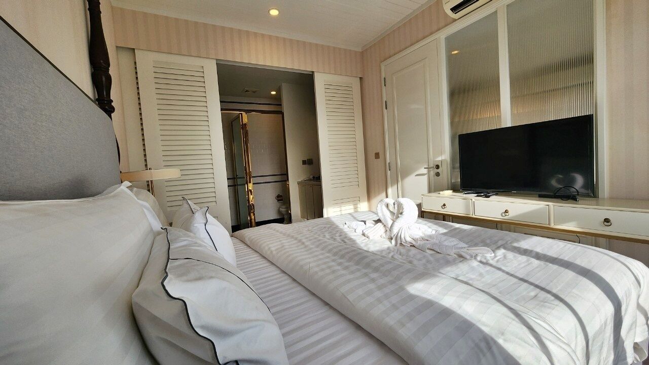 Una habitación de hotel con una cama grande, televisor, armario y espejo.