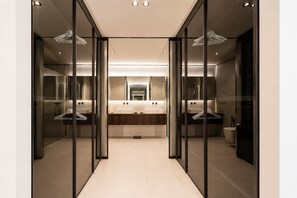 Ein modernes Badezimmer mit Glastrennwand, einem zentralen Waschbecken und einer Toilette.