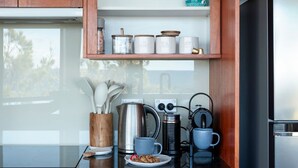 A kitchen with a stainless steel kettle, a coffee maker, and a plate of cookies.