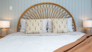 A bed with a woven headboard, two bedside lamps, and a patterned pillow set.