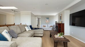A modern living room with a sectional sofa, a wooden coffee table, and a flat-screen TV mounted on the wall.