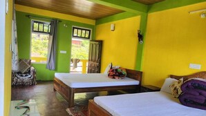 A room with two wooden beds, a small table, a chair, and a window with curtains. - Nambang Homestay Tinchuley (Darjeeling)