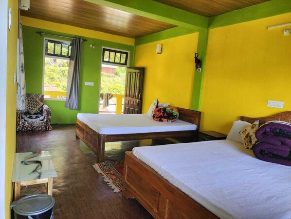 Una habitación con dos camas de madera, una mesita, una silla y una ventana con cortinas.