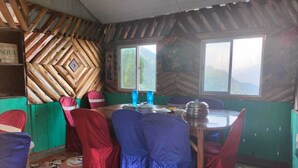 A dining area with a wooden wall, a window, and a table set for four. - Nambang Homestay Tinchuley (Darjeeling)