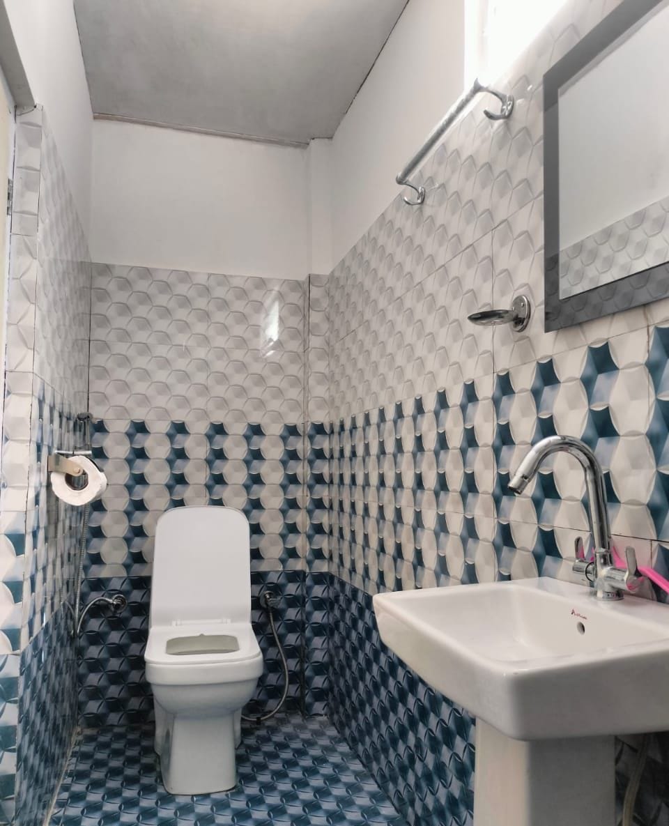 Et badeværelse med toilet, vask og fliserede vægge.