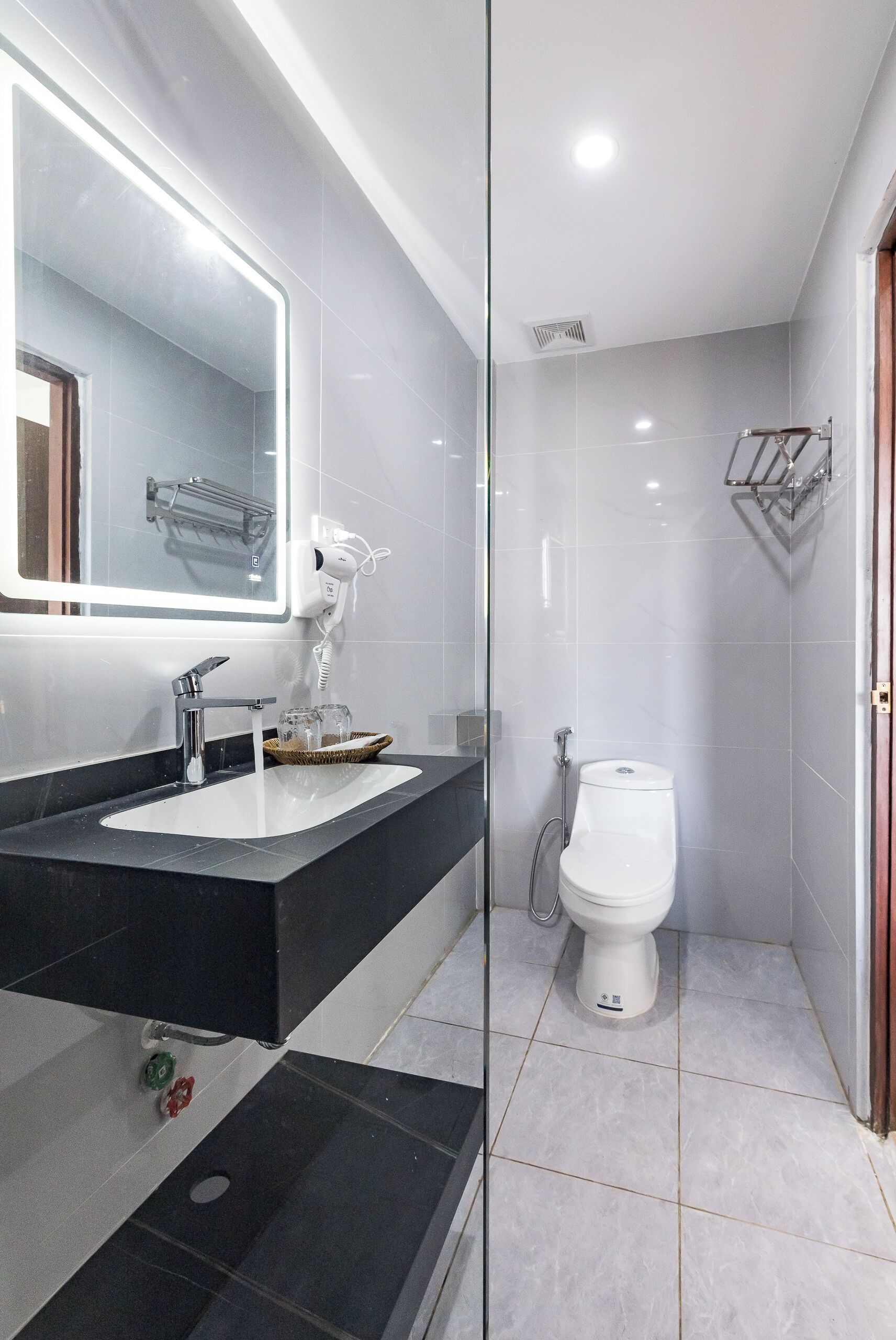 Een moderne badkamer met een douchecabine van glas, een wit toilet en een zwart aanrecht met een wastafel.